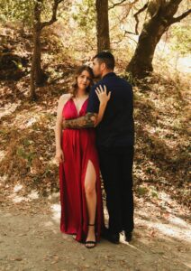 Woman wearing a long red dress and embracing a man in a suit. She is working on her confidence in dating.
