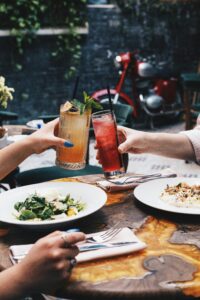 Two people cheers-ing drinks at dinner. They are on a date.