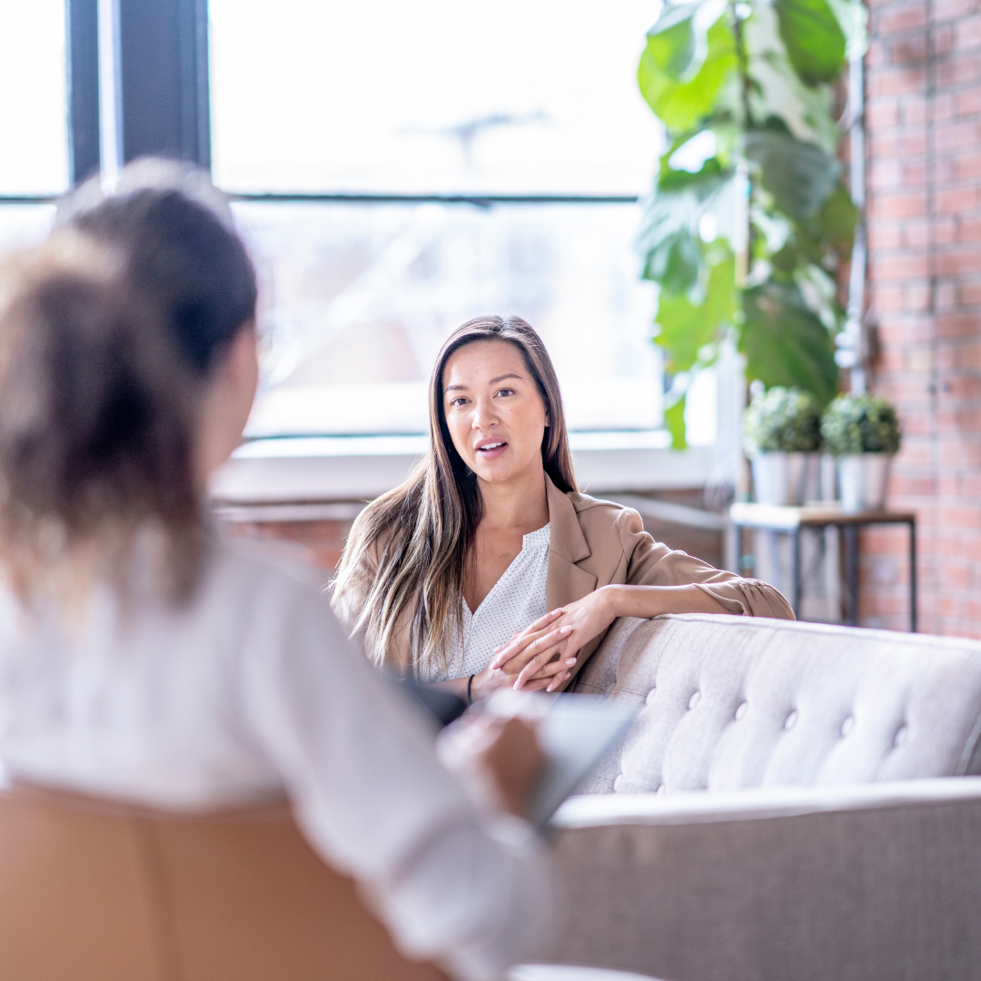 A woman talking to an anxiety therapist in a bright modern office. Showing what you can expect from anxiety therapy at Manhattan Wellness in New York. This include CBT for anxiety.