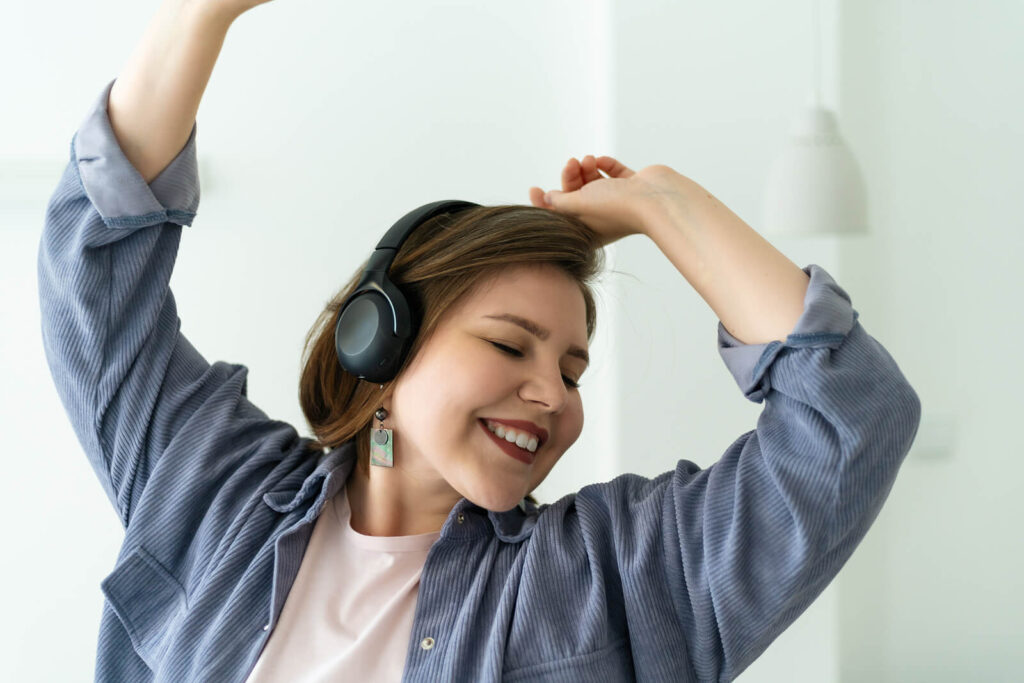 A woman wearing headphones smiling and dancing. Representing someone who go help for their panic attacks from an anxiety therapist in Manhattan, NY. If you want to feel like this reach out to start anxiety therapy or treatment for social anxiety in Manhattan or Brooklyn!