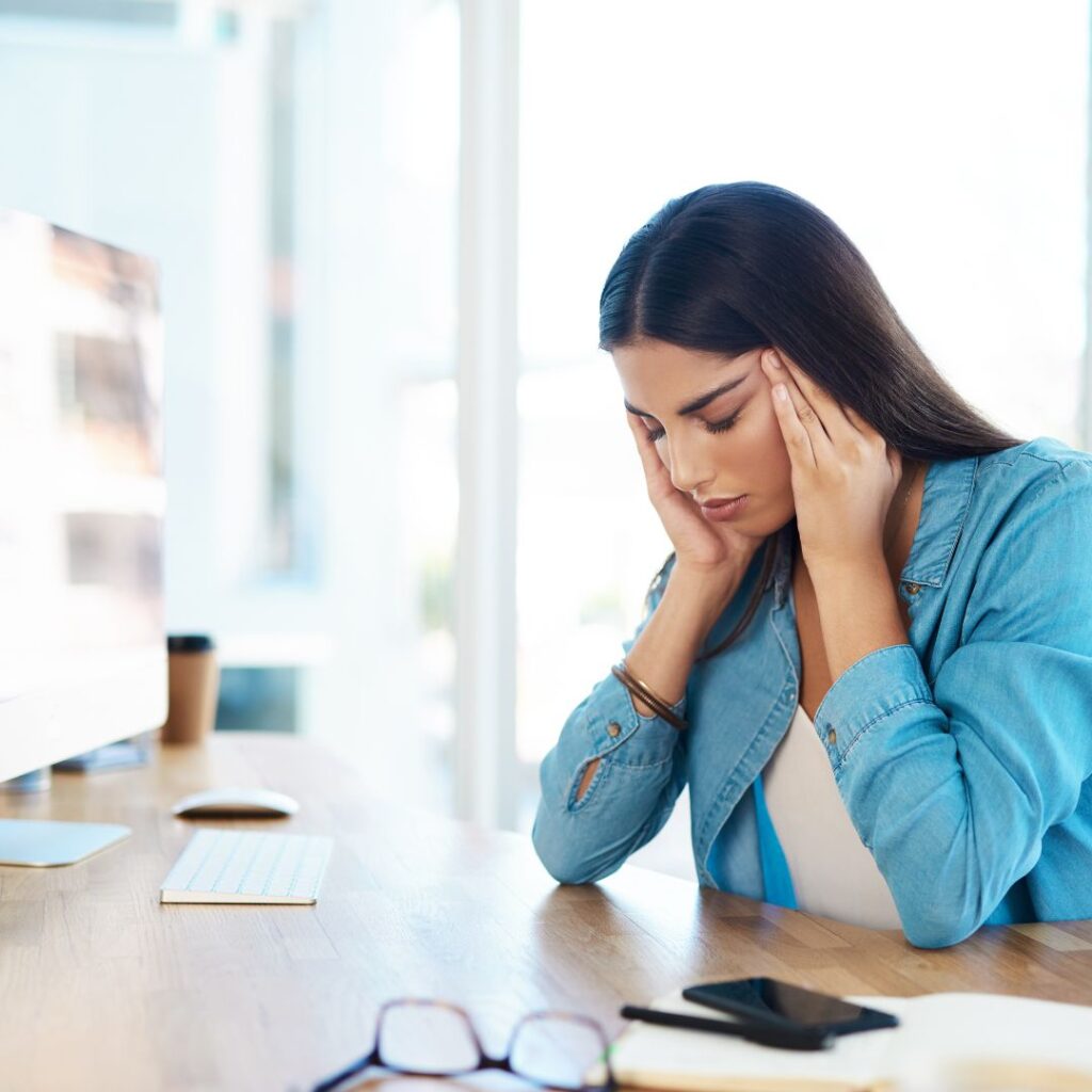 A woman holding her head in front of a computer in an office building in Manhattan looking anxious and panic. This woman could benefit from tips form an anxiety therapist. If you get feelings like this get support with anxiety treatment for women in Brooklyn or Manhattan.
