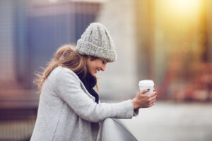 A woman holding a cup of coffee in New York. Showing the benefits that can come from meeting with a depression therapist in Manhattan or New York. You can get through your winter blues & reduce your depression symptoms with treatment.