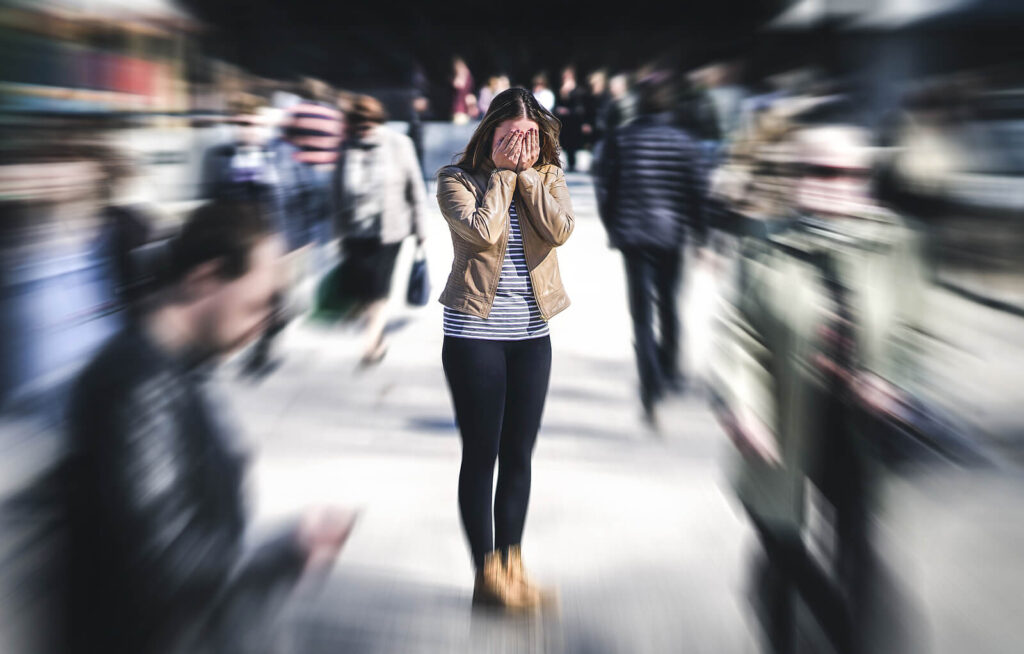A woman walking through a crowd of people in Brooklyn looking anxious. representing someone who could benefit from CBT for anxiety. If you get feelings like this get support with anxiety treatment for women in Brooklyn or Manhattan.
