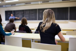 A university classroom where a teacher is writing on a blackboard. Representing the importance of academic & social balance which is encouraged in online therapy for college students in New York. Whether you are in Brooklyn or Manhattan you can get support today in counseling for college students.