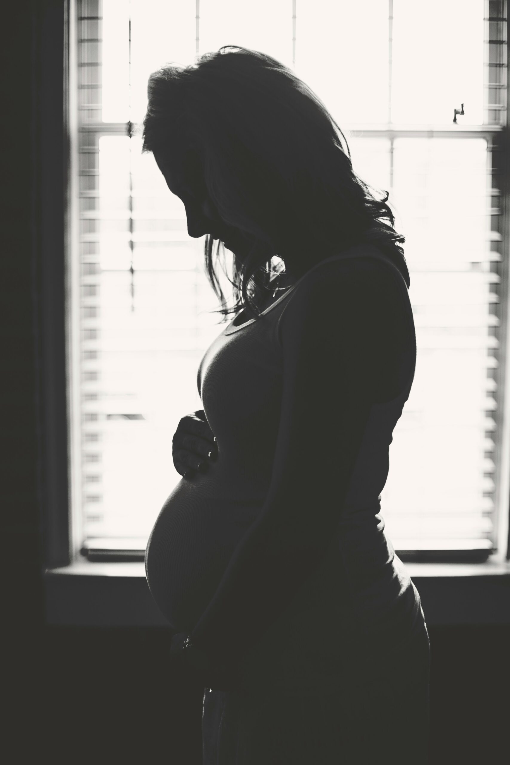 black and white picture of a pregnant woman holding her stomach in Manhattan. Therapy can help you with pregnancy and your fertility journey.