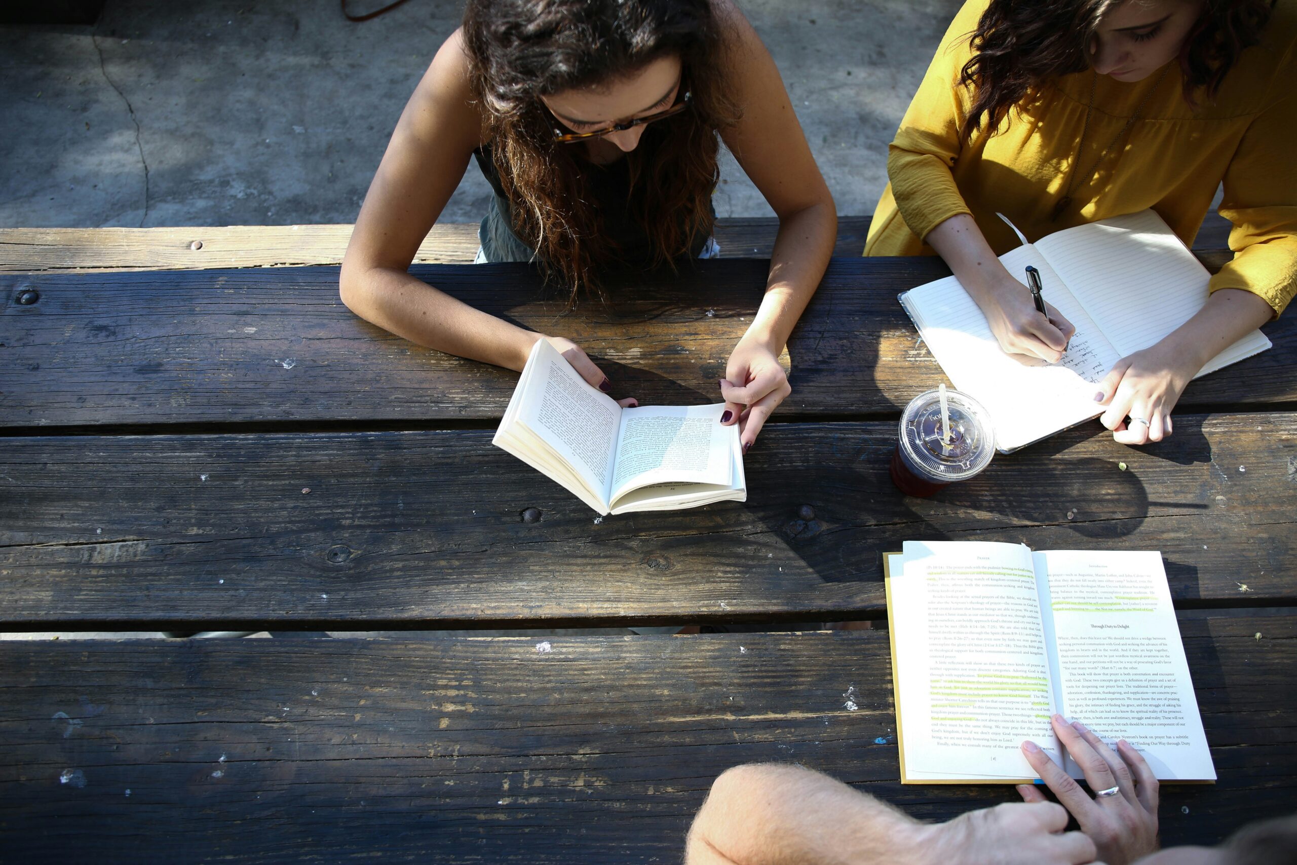 Women sitting around an outside table in NYC writing in their journals. Manhattan group therapy for eating disorders provide strategies and tools for recovery.
