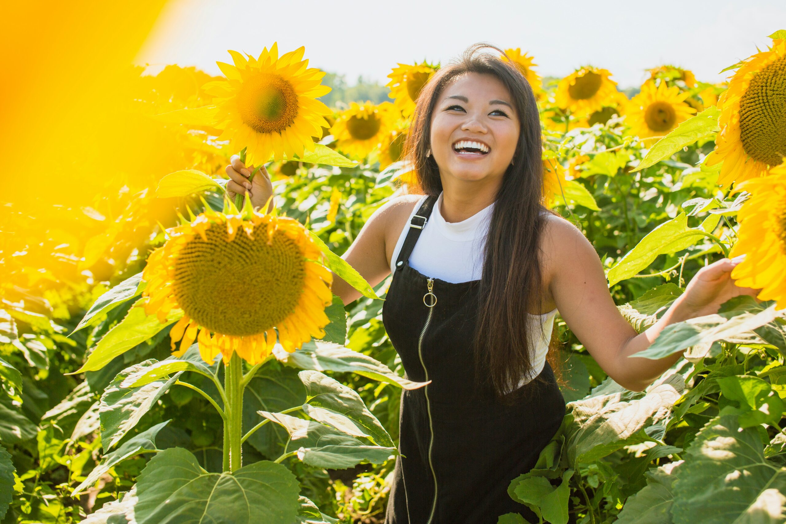 Smiling, confident woman standing in a sunflower field. Therapy in Manhattan can help you feel more confident and boost your self-esteem.