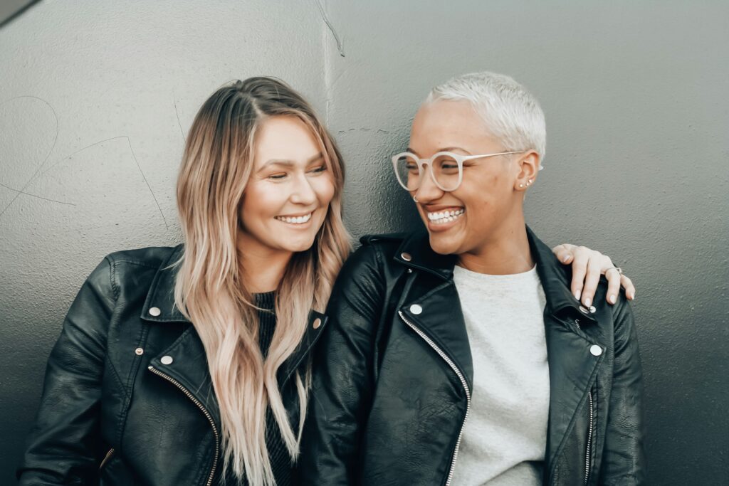 Two women in leather jackets, smiling and enjoying each other in Brooklyn. Comfort and trust can establish a sexual attraction even if there isn't one from the start. 