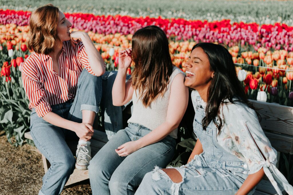 women sitting in a flower field in Brooklyn, laughing and joking around. Eating disorder recovery can be made easier by identification of your triggers and helpful coping skills. 