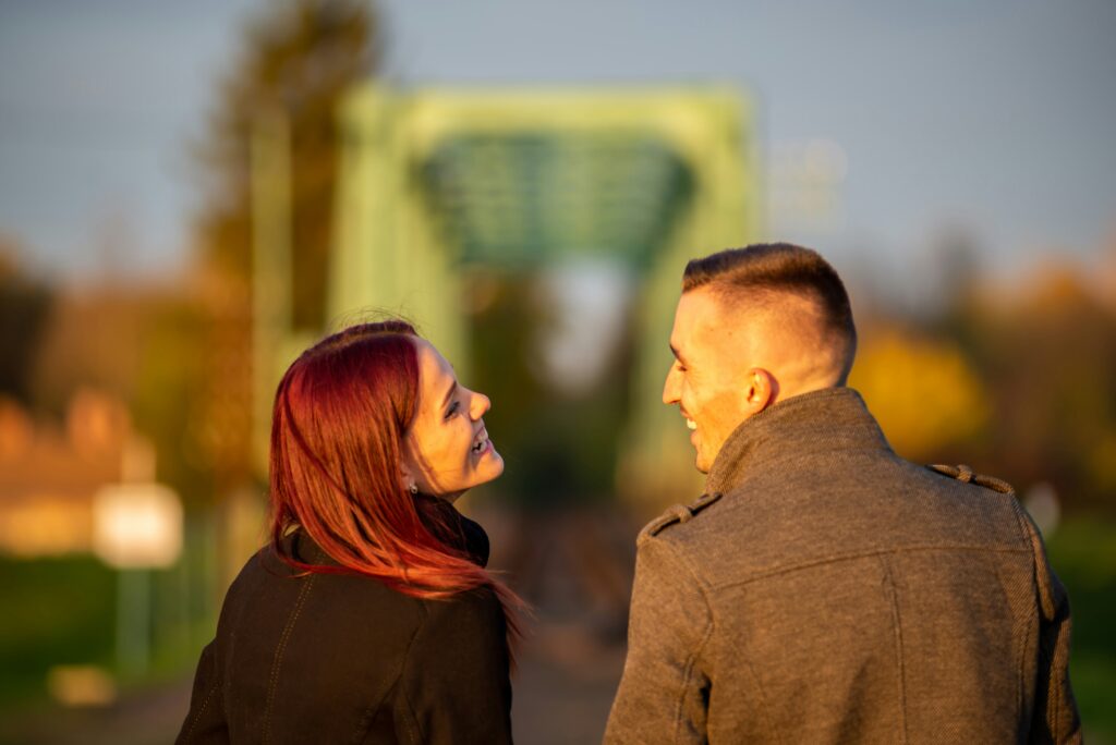 A Brooklyn man and a woman looking at each other with smiles on their face with a bridge in the background. Learning more about attachment styles can help your relationship flourish. 