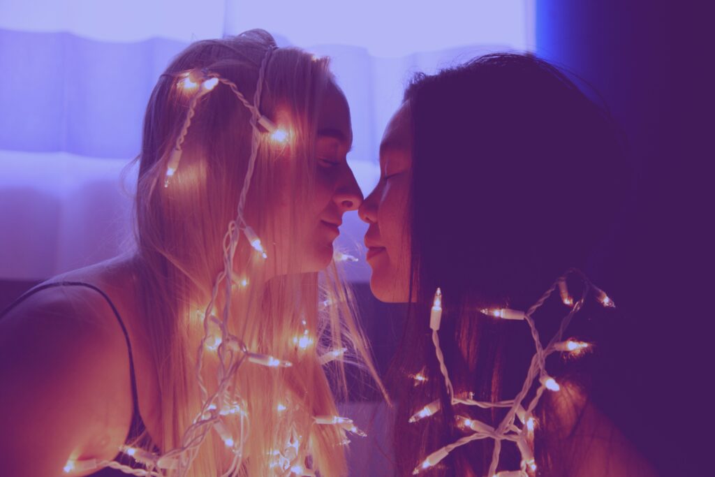 Two New York City women wrapped in twinkle lights, about to kiss. Its important to know your attachment style in relationships. 