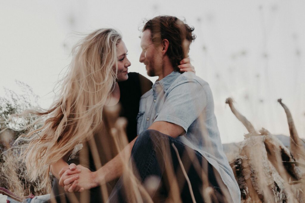 A Manhattan man and a woman, looking lovingly into each other sitting in a field. Knowing your attachment style is important to your relationships.