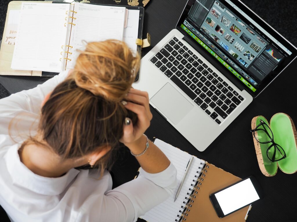 Manhattan woman leaning over her computer, stressed with her workload. Depression and sadness may be similar, but there are key differences. 