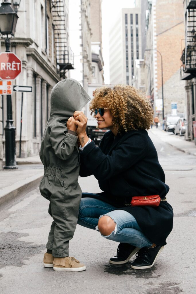 Manhattan mom standing on a street playing with her child. Maternal mental health can improve with therapy. 