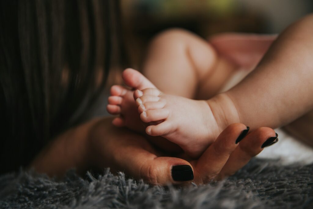 Woman playing with her baby's feet in Manhattan. Your fertility journey may be hard and long, but therapy can help you explore all your feelings and emotions. 