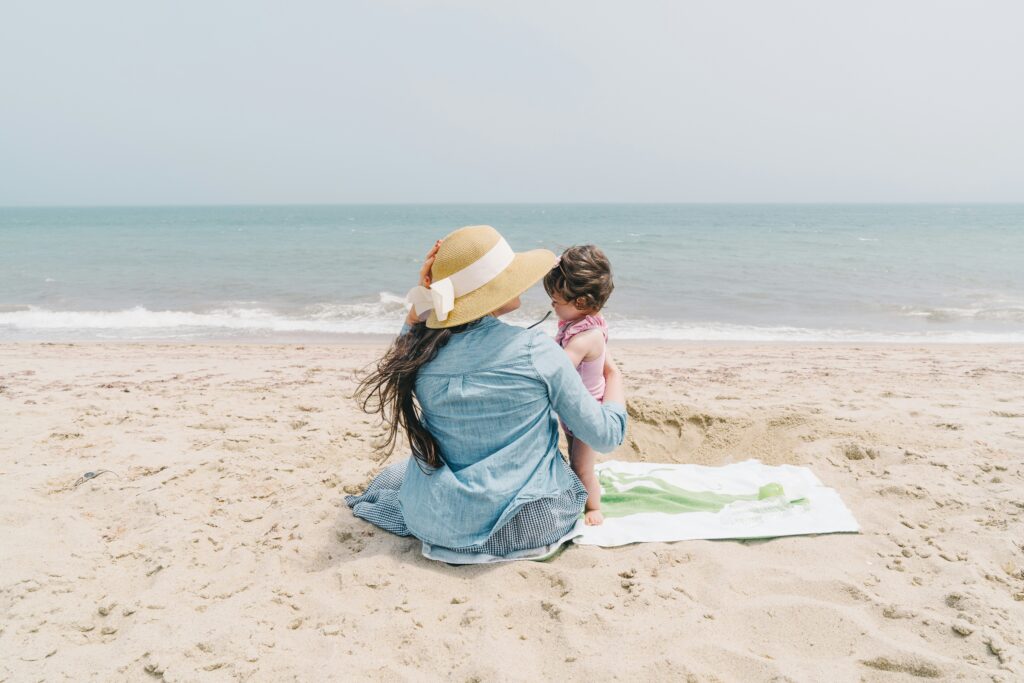 Manhattan mom at the beach with her toddler. Balancing motherhood with all of your other roles is hard. Therapy can help. 