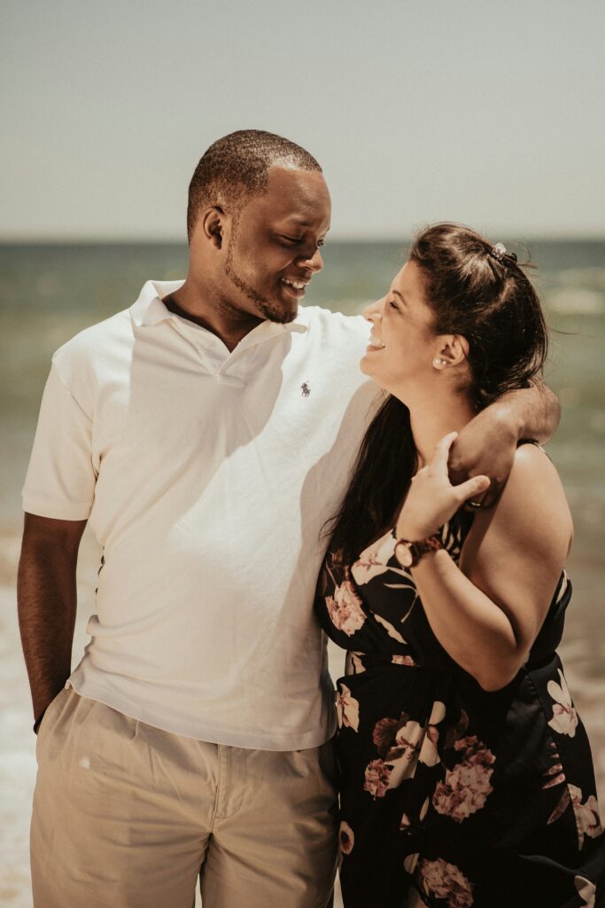 Happy Brooklyn couple looking into each other eyes on the beach. Insecurities in relationships can hold you back from fully experiencing the depth of your relationship. 