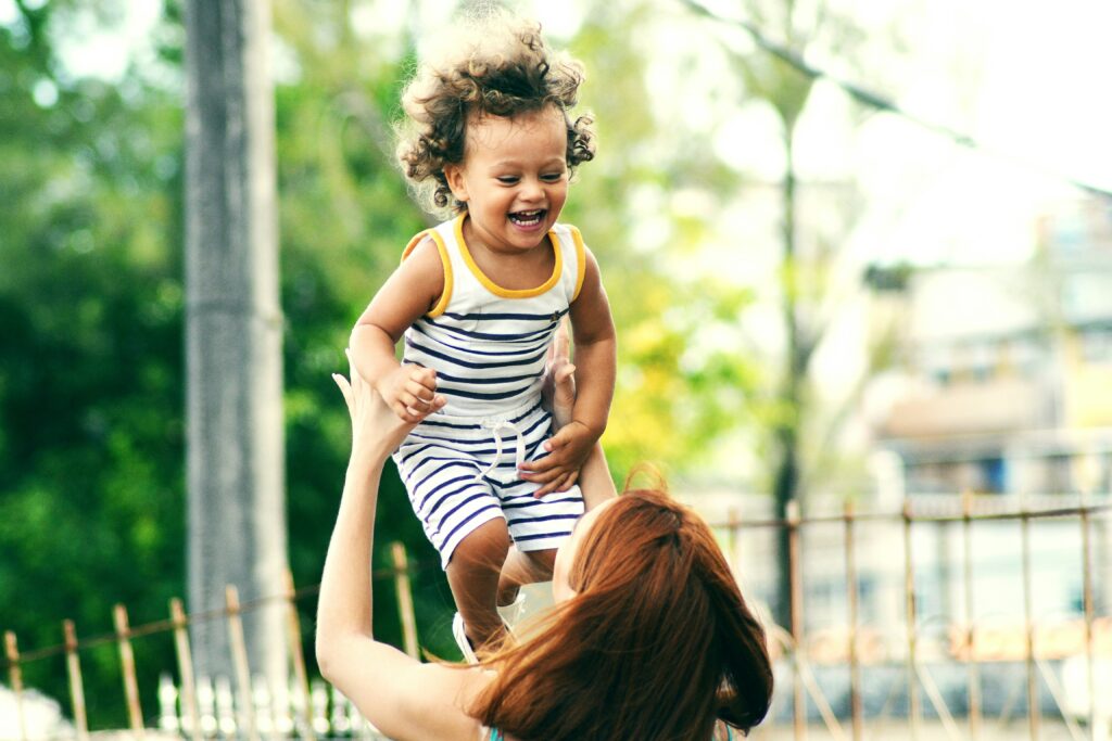 New York toddler being thrown in the air by his mom. Motherhood can affect your mental health; therapy can help. 