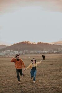 Brooklyn couple running through a field hand in hand. Communication is an important part of relationships and dating.