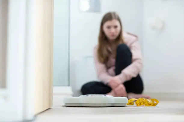 Manhattan woman sitting in a bathroom staring at a scale.
