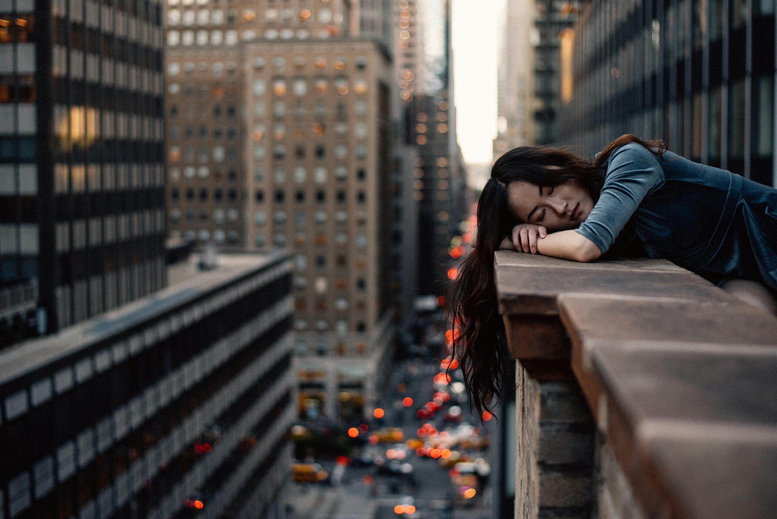 Manhattan woman resting her head on her balcony edge. Trauma can impact body image. Therapy can help.