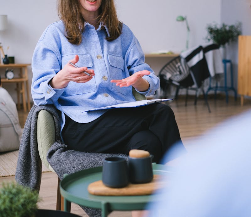 Picture of a therapist talking, using her hands, with a clipboard and pen.