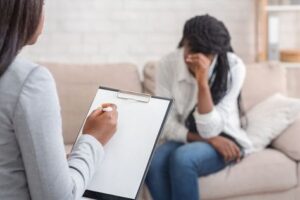 Manhattan woman sitting in a therapy session, with her hand on her head. Therapy can help treat depression.