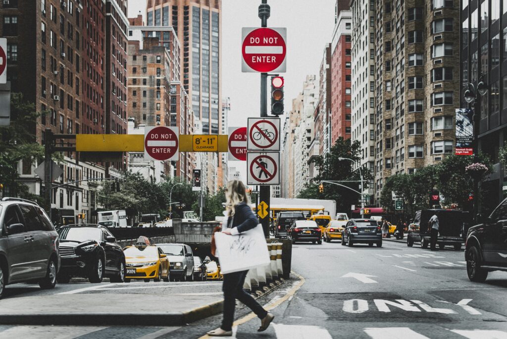 New York City woman shopping in Manhattan, carrying her bags across an intersection. Trauma and body image go hand in hand. Therapy can help. 