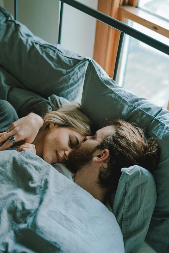 Couple in bed together, man kissing woman's forehead.