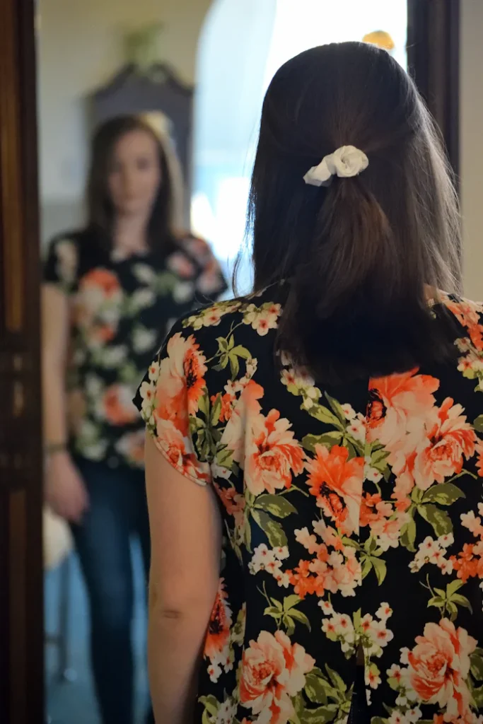 Woman looking in the mirror at her reflection. She is working on her body image in therapy.