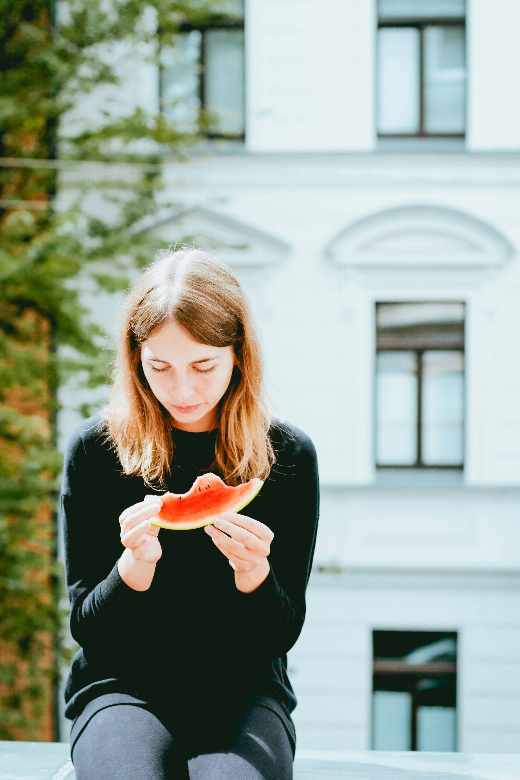 Woman looking at and eating a piece of watermelon.