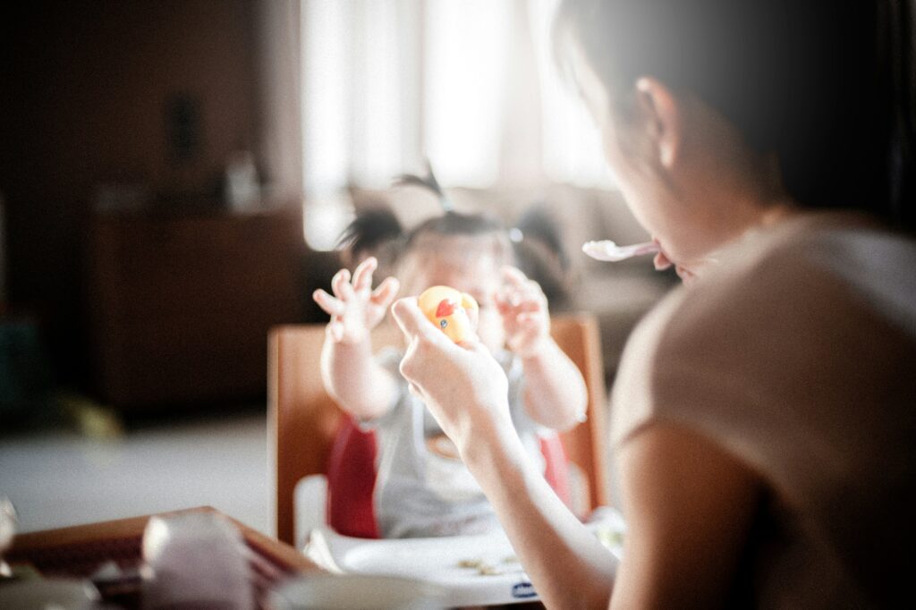 Mom feeding baby while holding toy in other hand.