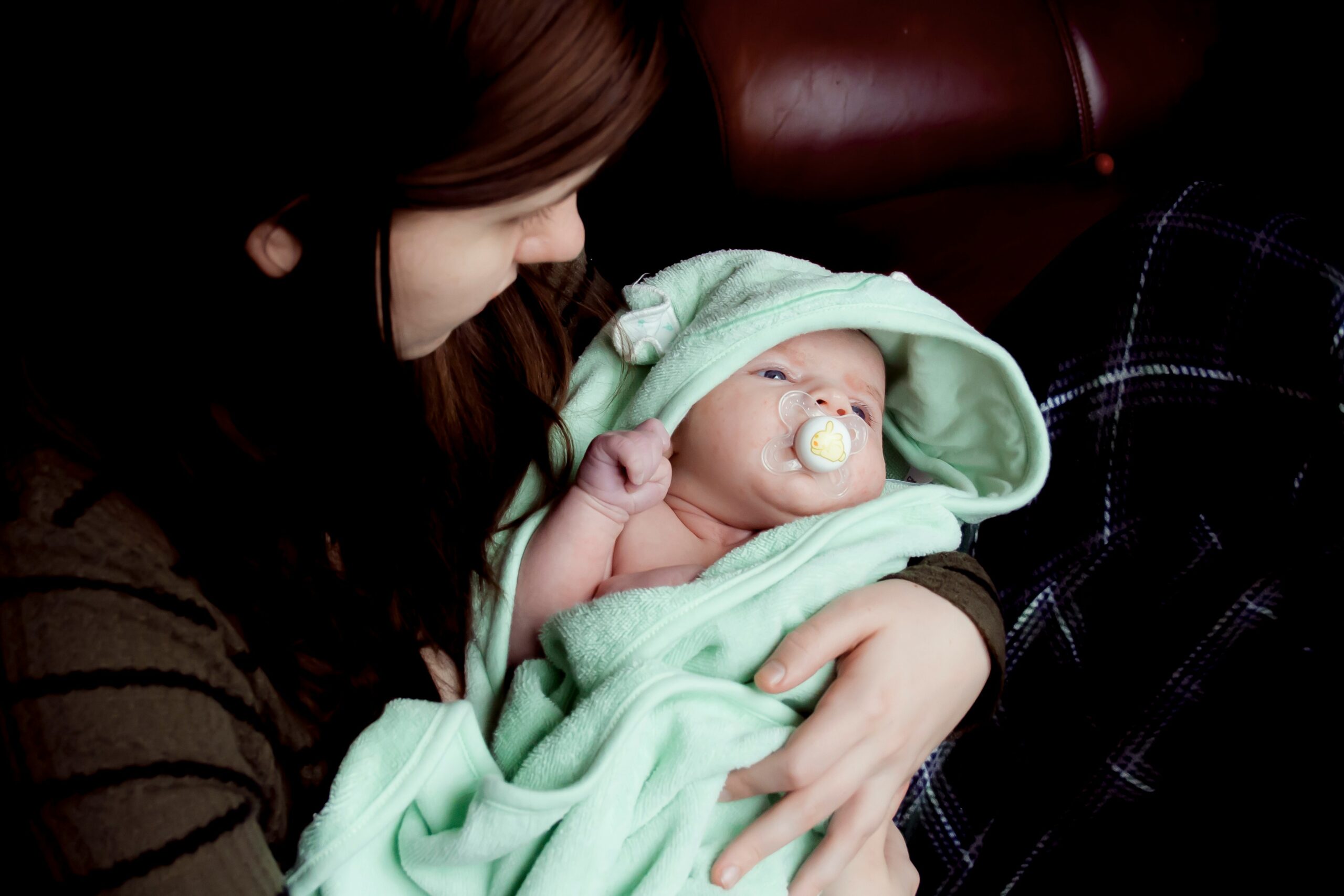 Mom holding her baby with a pacifier in her arms. This woman could benefit from tips form a therapist. If you get feelings like this get support with maternal therapy treatment for women in Brooklyn or Manhattan.