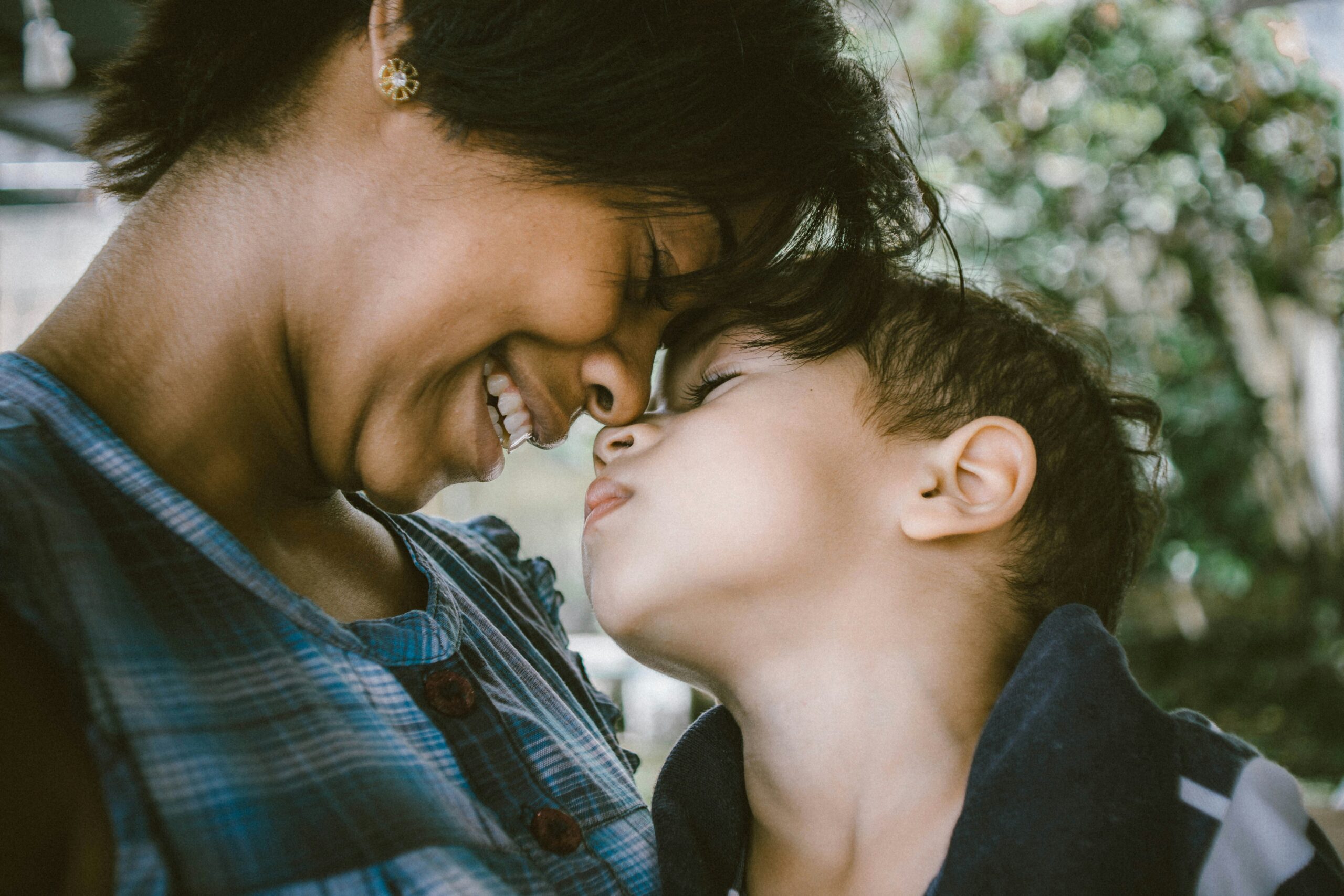 Mom and toddler smiling with their heads together.