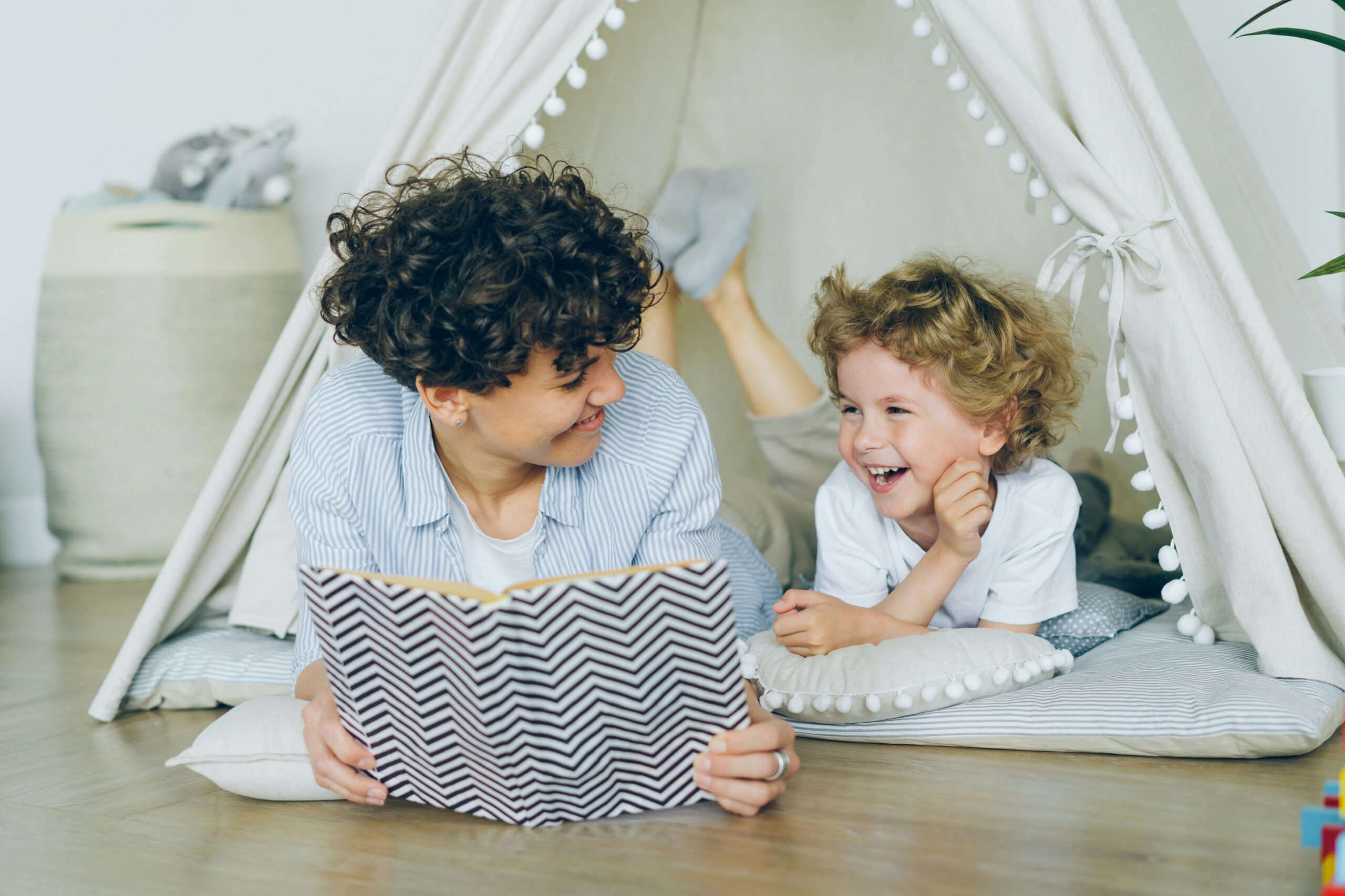 Mom reading a book to her son, both smiling.