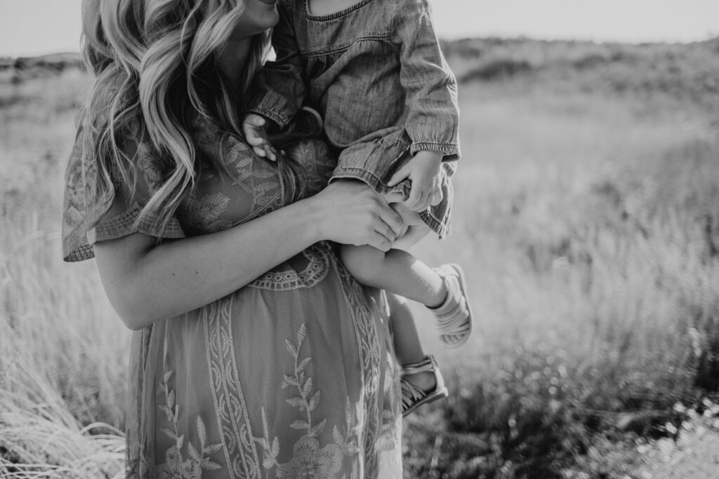 Black and white image of pregnant mom holding her other child