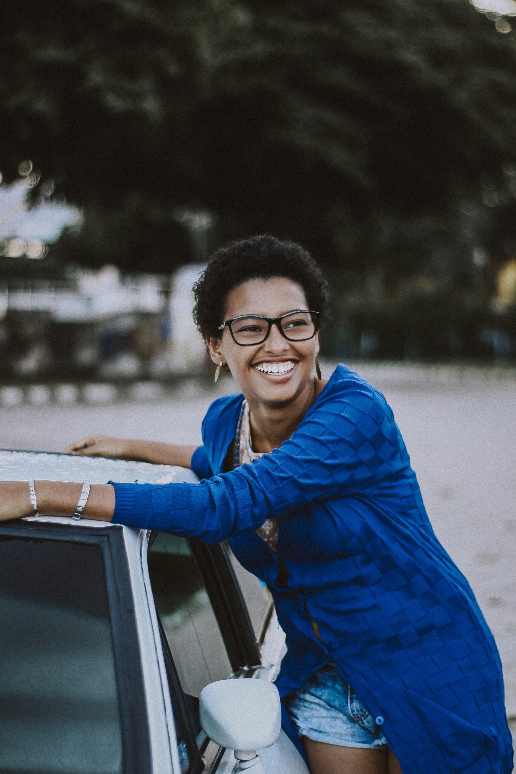 Woman standing smiling next to a car.