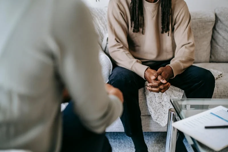 Man sitting in therapy session, hands together.