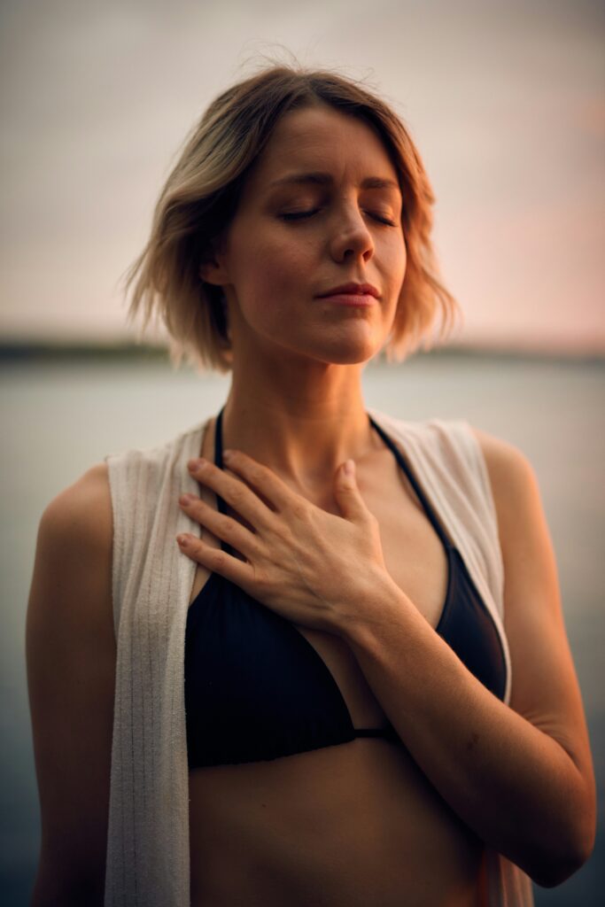 Woman taking deep breaths, with her hand on her chest and eyes closed.