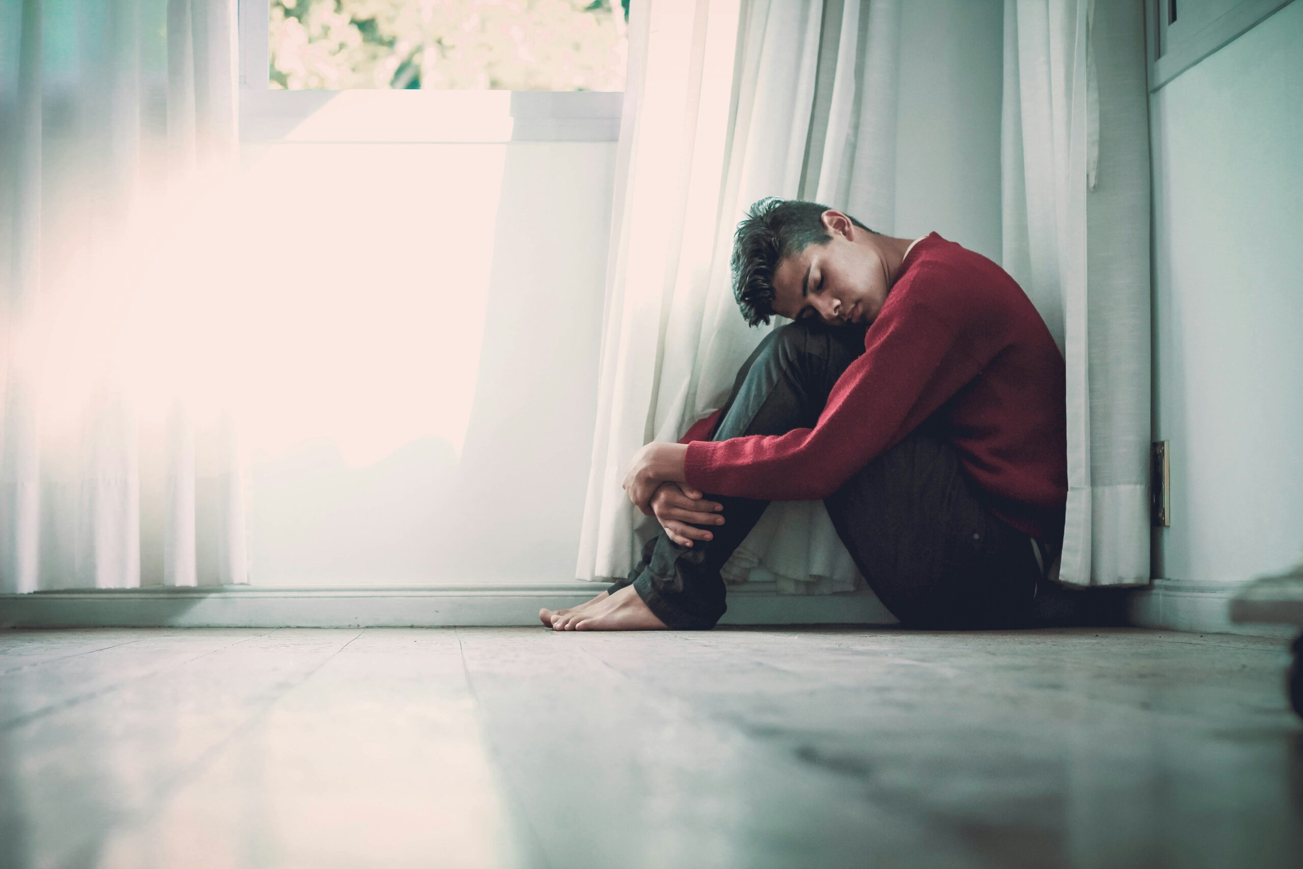 Man with his head on his knees and his eyes closed.