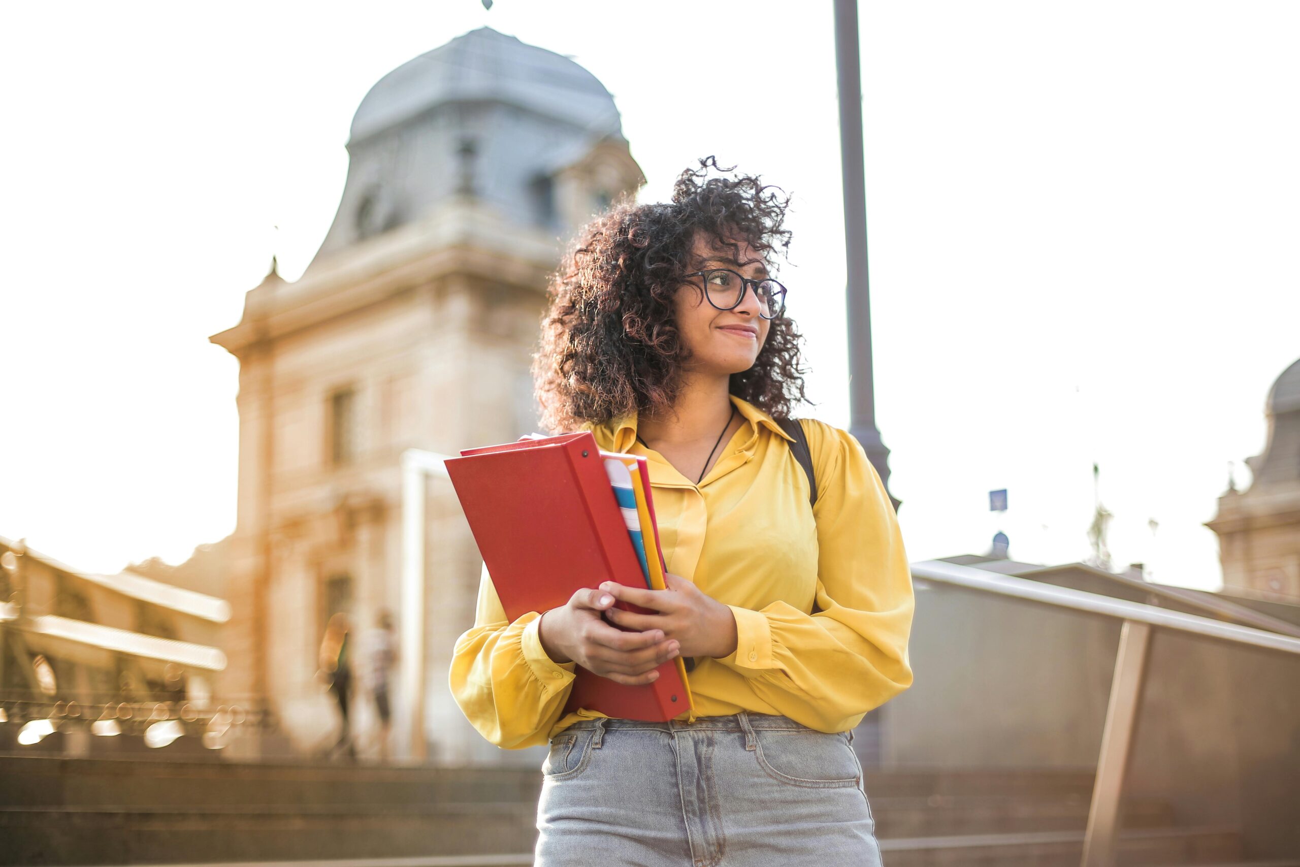 Girl holding books smiling looking away.