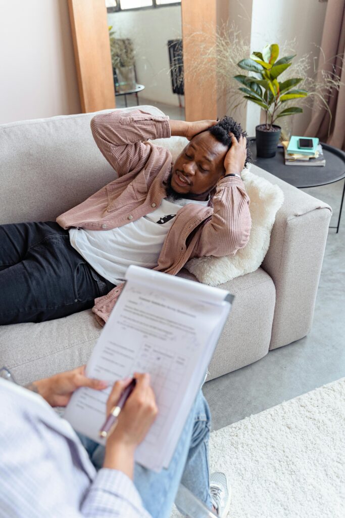 Man laying on couch holding his head in therapy.