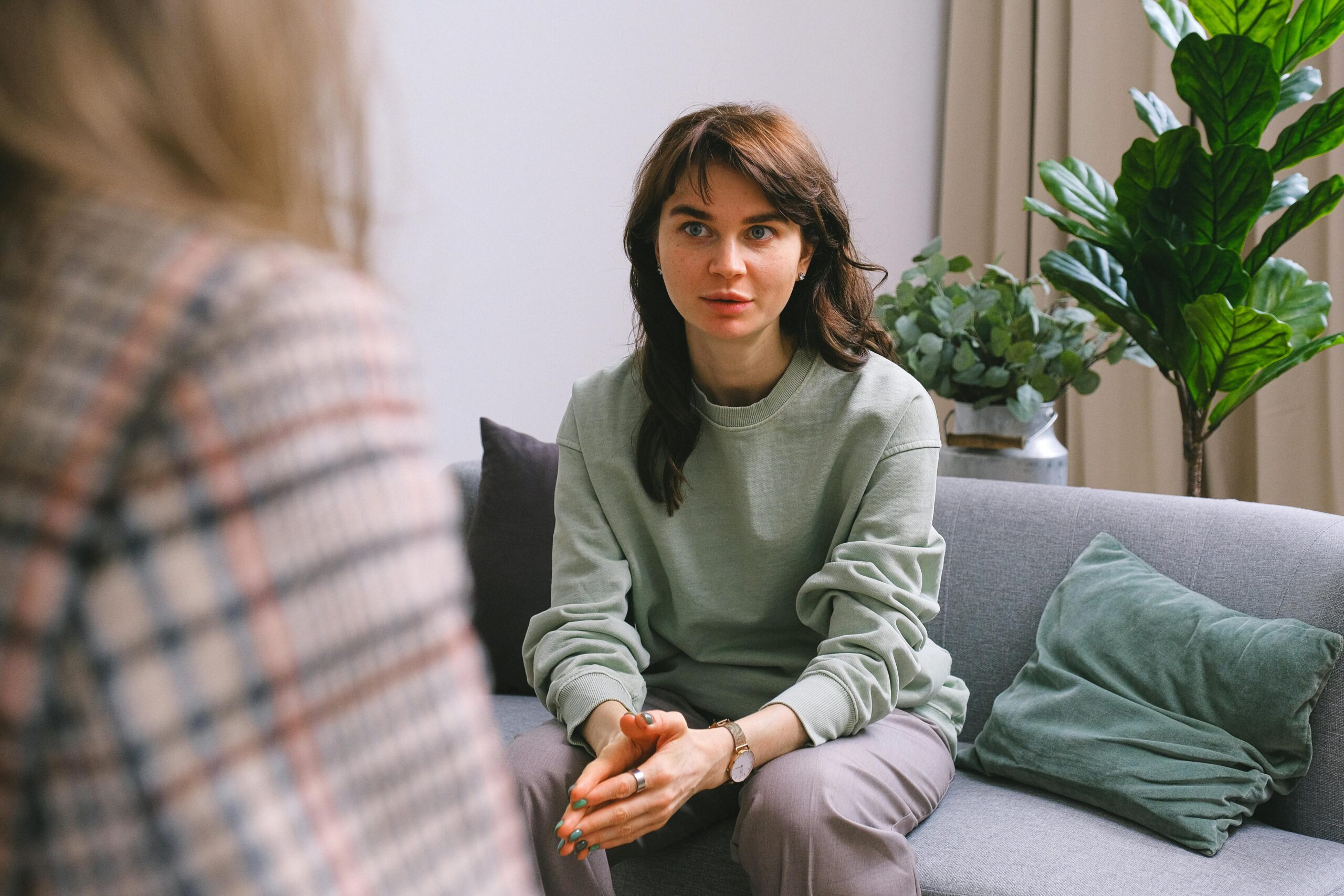 Woman sitting in her therapy session, hands together.