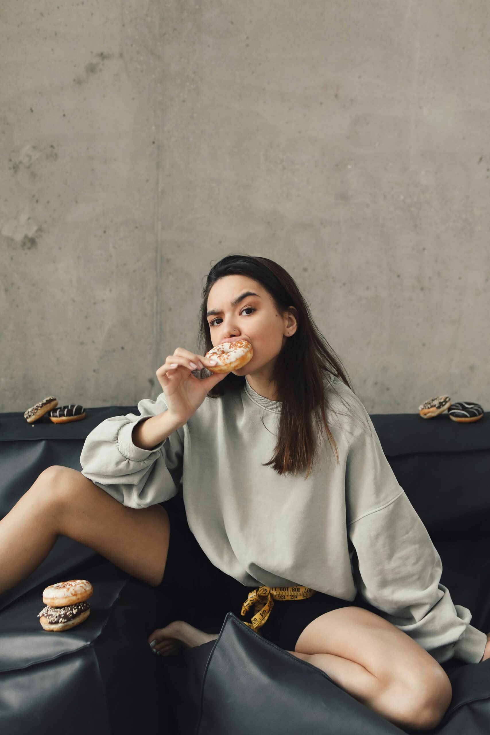 Woman eating donuts with measuring tape around her.