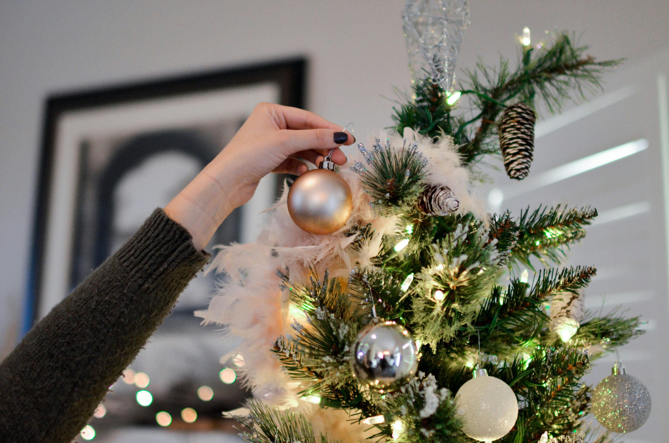 Putting ornament on Christmas tree.