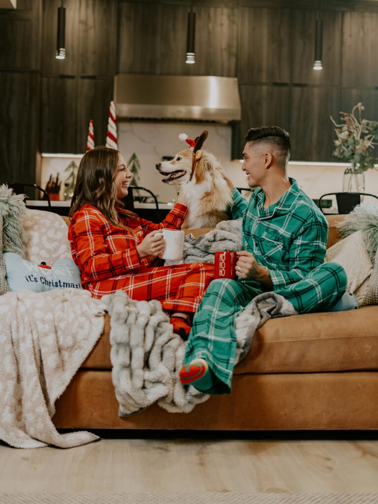 Couple in matching pajamas on the couch with their dog.