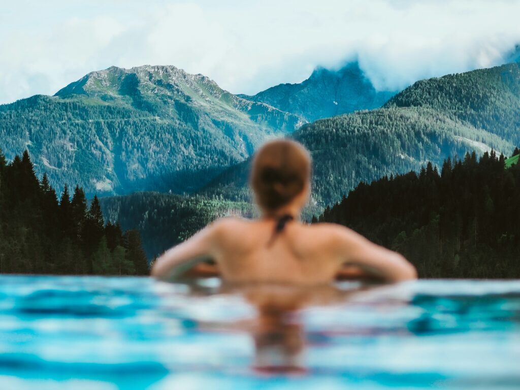 Woman in the water looking out at the mountains in front of her.