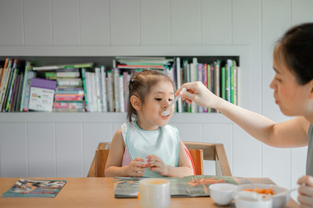 Mom feeding her child at the table.