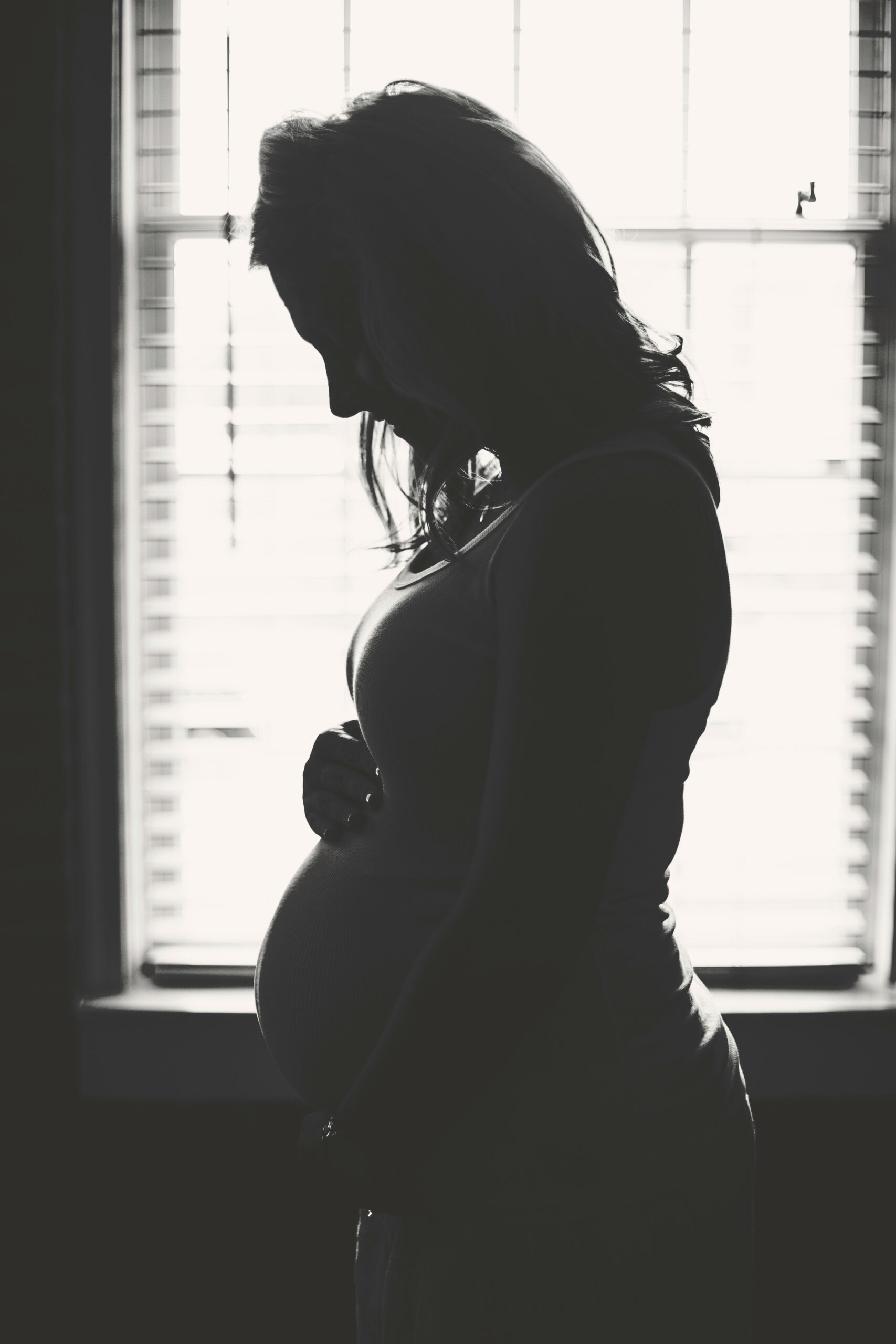 Black and white photo of a pregnant woman holding her stomach.