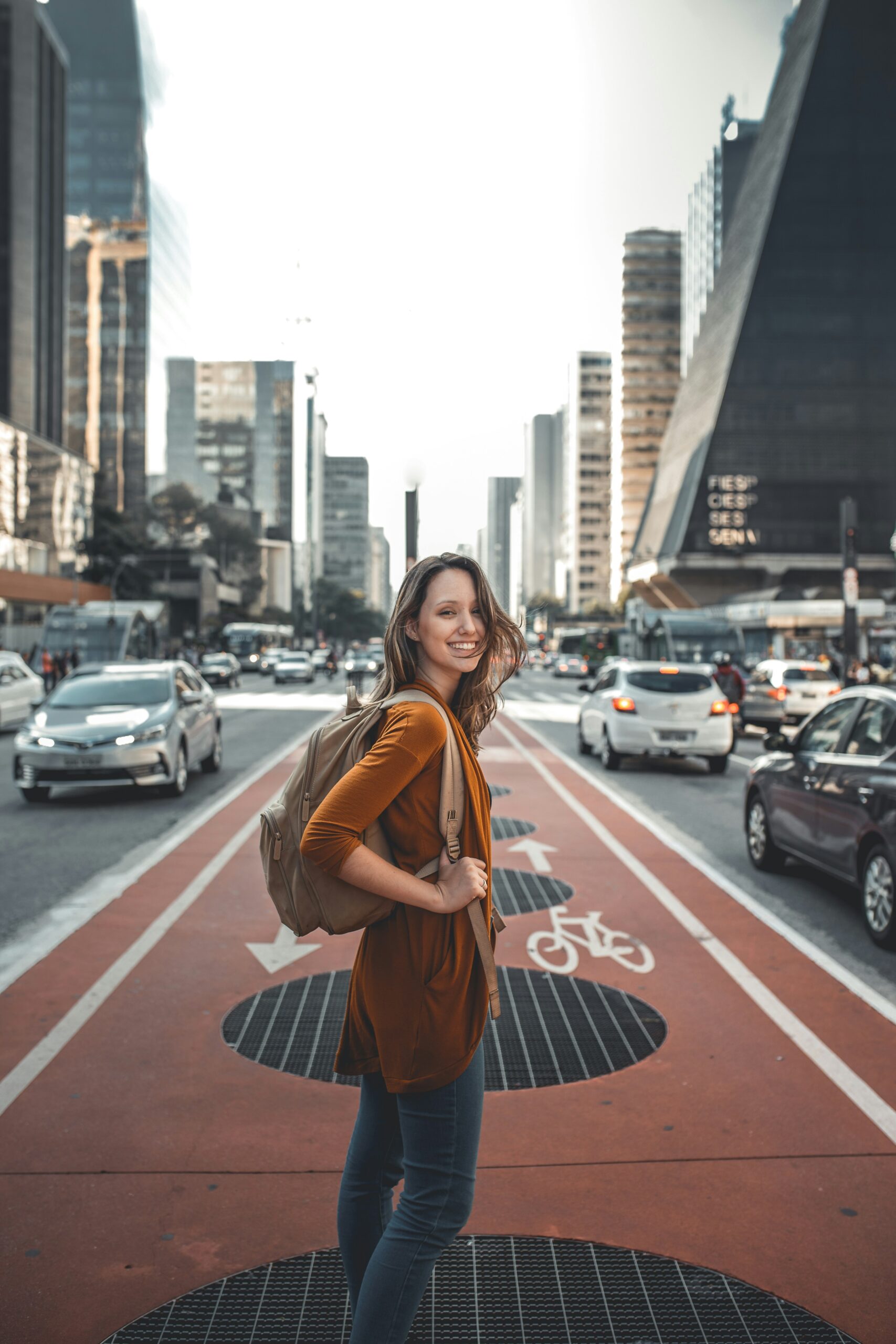 Woman smiling walking with her backpack in the street.